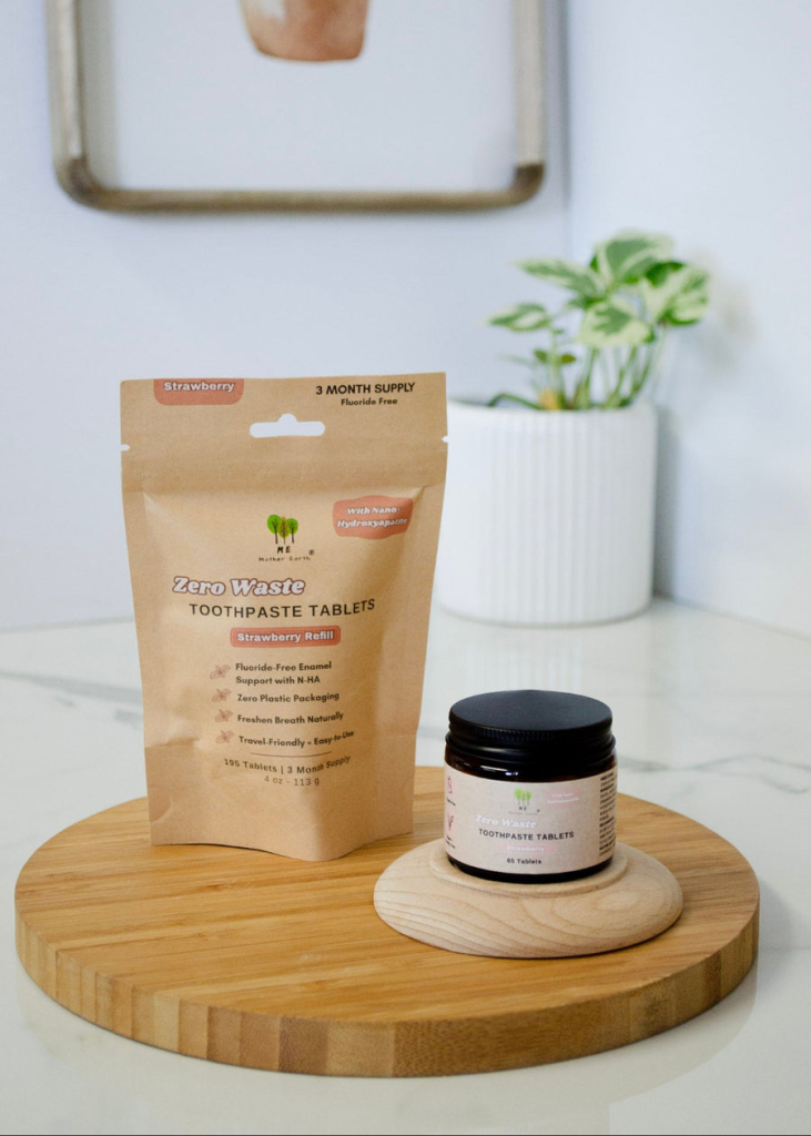 Me Mother Earth toothpaste tablets in a glass jar next to a refills in a compostable pouch.