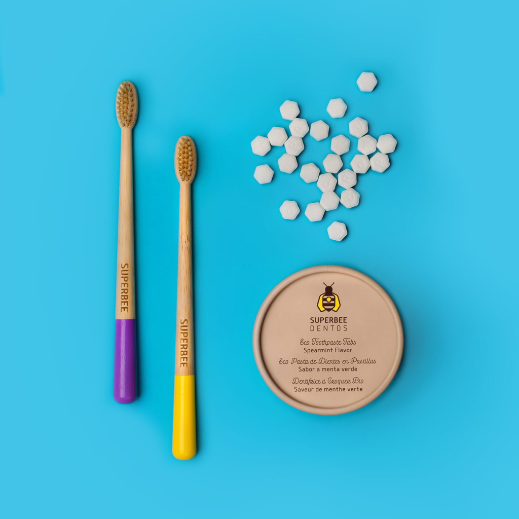 Superbee toothpaste tablets shaped like hexagons next to wooden toothbrushes